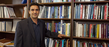 Azim  Eskandarian stands in front of books on stacks
