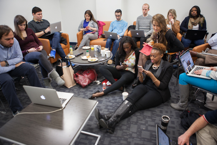 Group of students in lounge around laptops and mobile views live tweeting Meet the Press