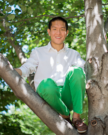 Max Chen sitting on tree branch smiling