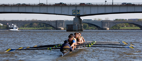 rowing team on boat in below Roosevelt Bridge where GW is painted on