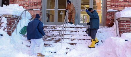 Workers shoveling steps of academic building