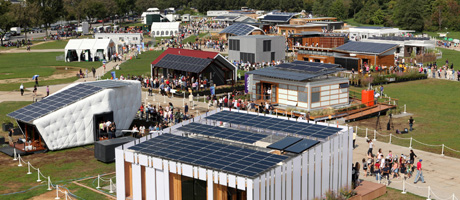 Aerial view of solar paneled building exterior at U.S. Department of Energy Solar Decathlon 2011 with visitors walking grounds 