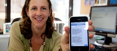 Lorien Abroms holds up iPhone screen with Text2Quit texts on it