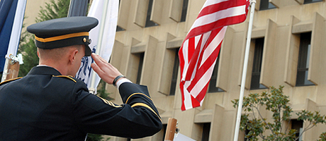 man in military uniform salutes American flag