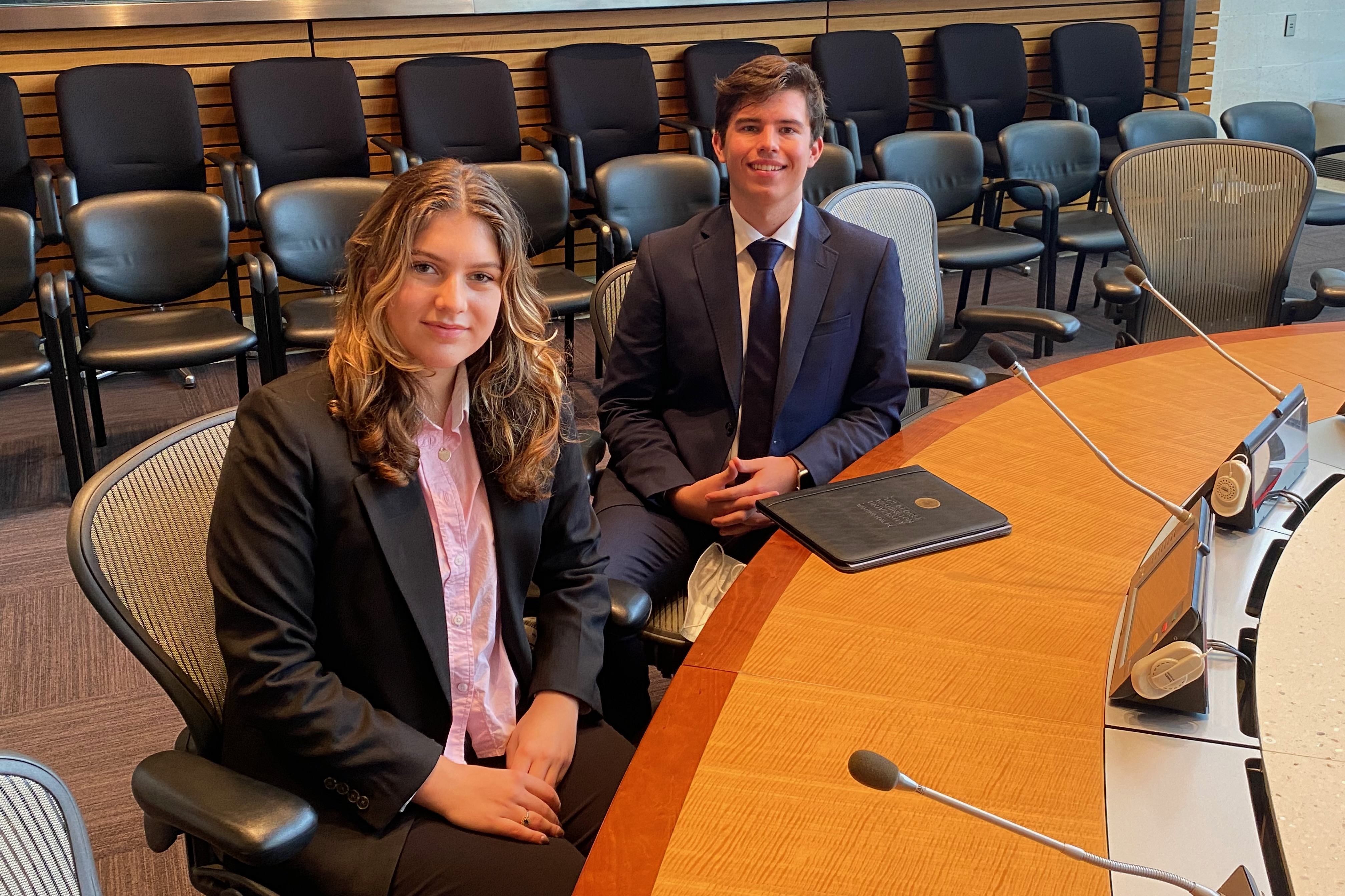 Two students sitting in a board room 