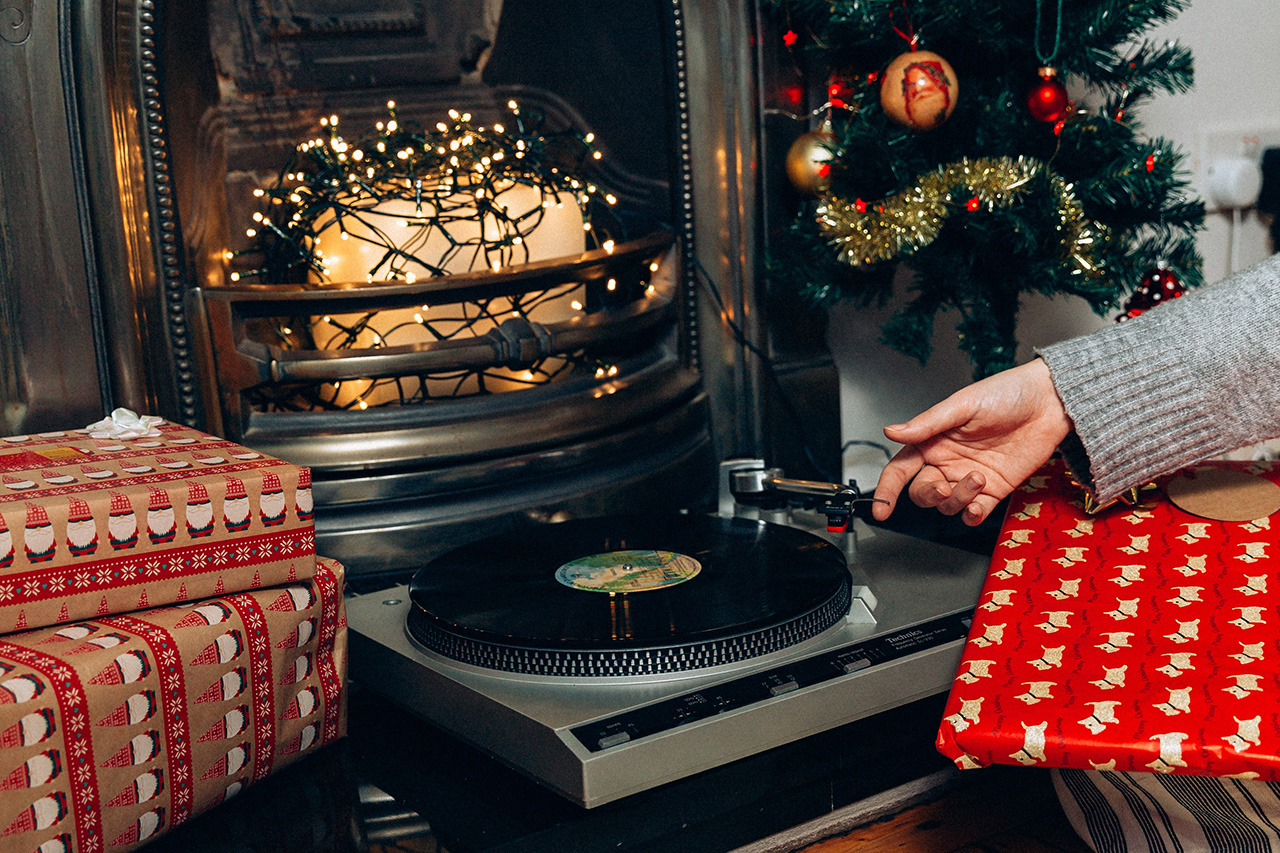 Record player in front of fireplace surrounded by wrapped gifts