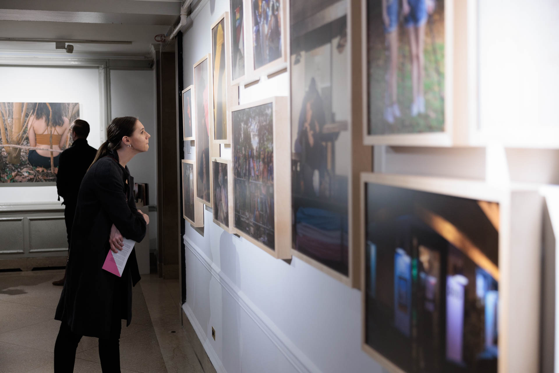 Two people study artworks on display at NEXT