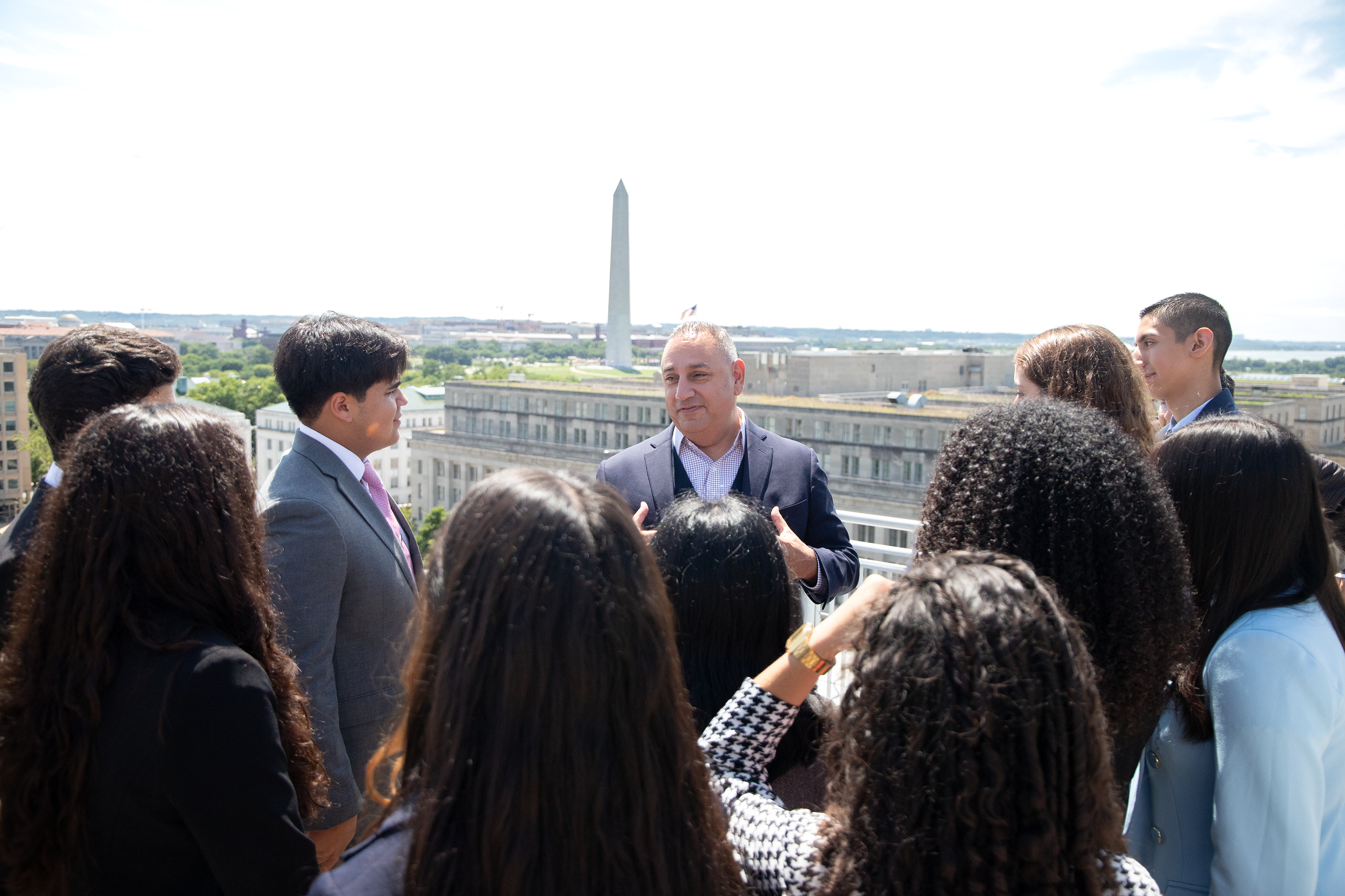 Gilbert Cisneros, B.A. ’94, spoke with students from the Caminos al Futuro on the terrace of the City View Room overlooking the Washington Monument. 