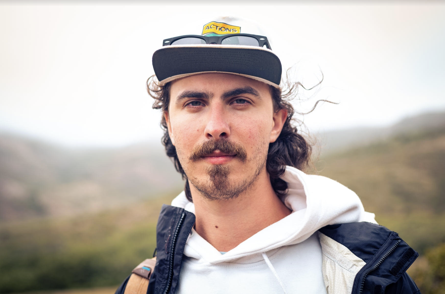 White male with a mustache and goatee hiking in the hills