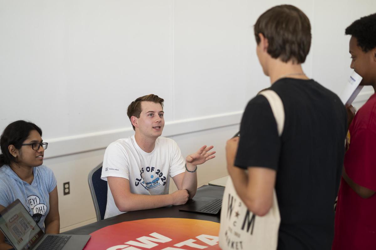A male student talks to two other students at Org Fair Friday
