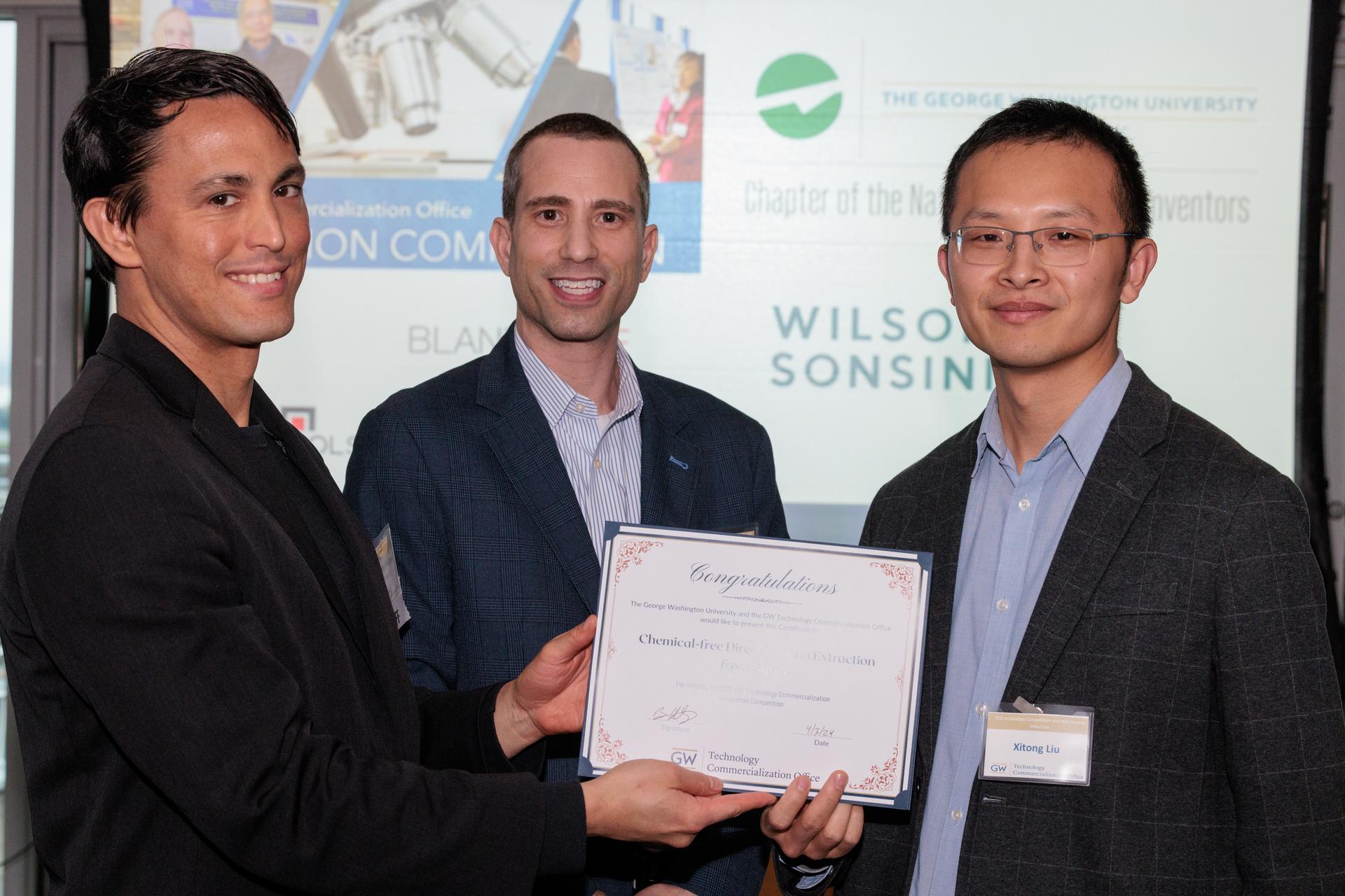 (Left to right) TCO Senior Licensing Manager of Physical Sciences Michael Harpen and TCO Executive Director Brian Coblitz present certificate to GW Engineering's Xitong Liu. 
