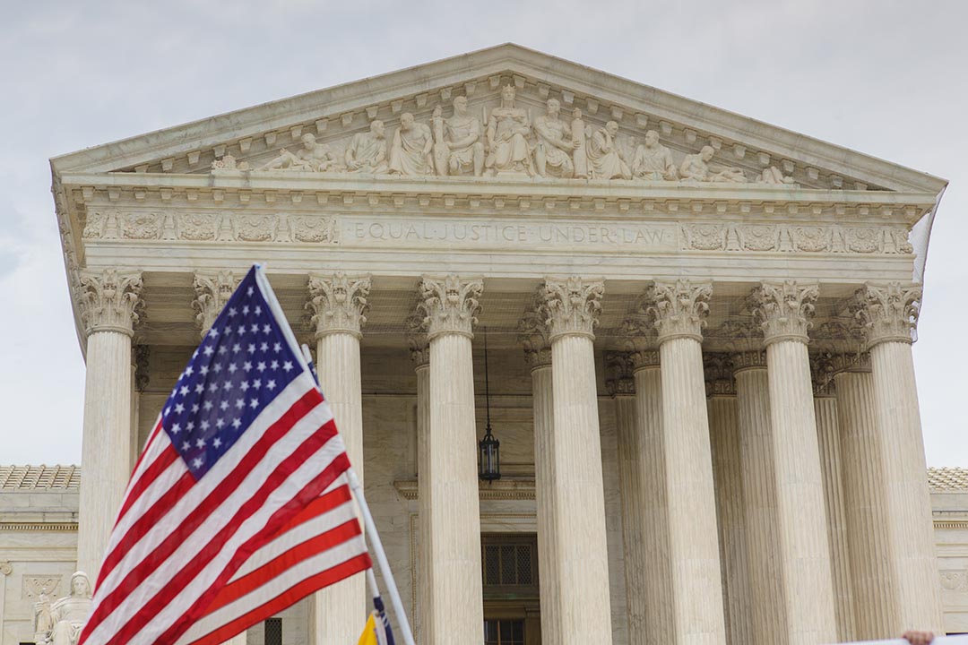 Facade of the U.S. Supreme Court with American flags in foreground 