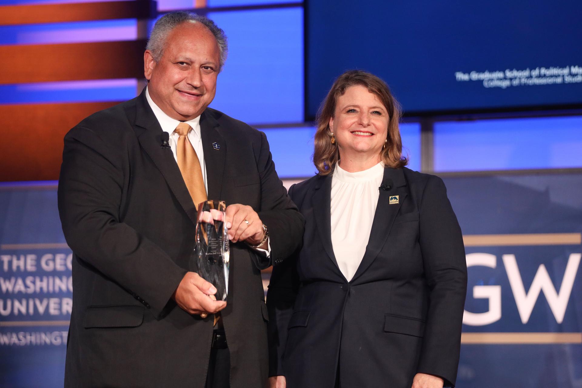 U.S. Navy Secretary Carlos Del Toro accepts the GSPM Alumni Lifetime Achievement Award presented by CPS Dean Liesl Riddle. 
