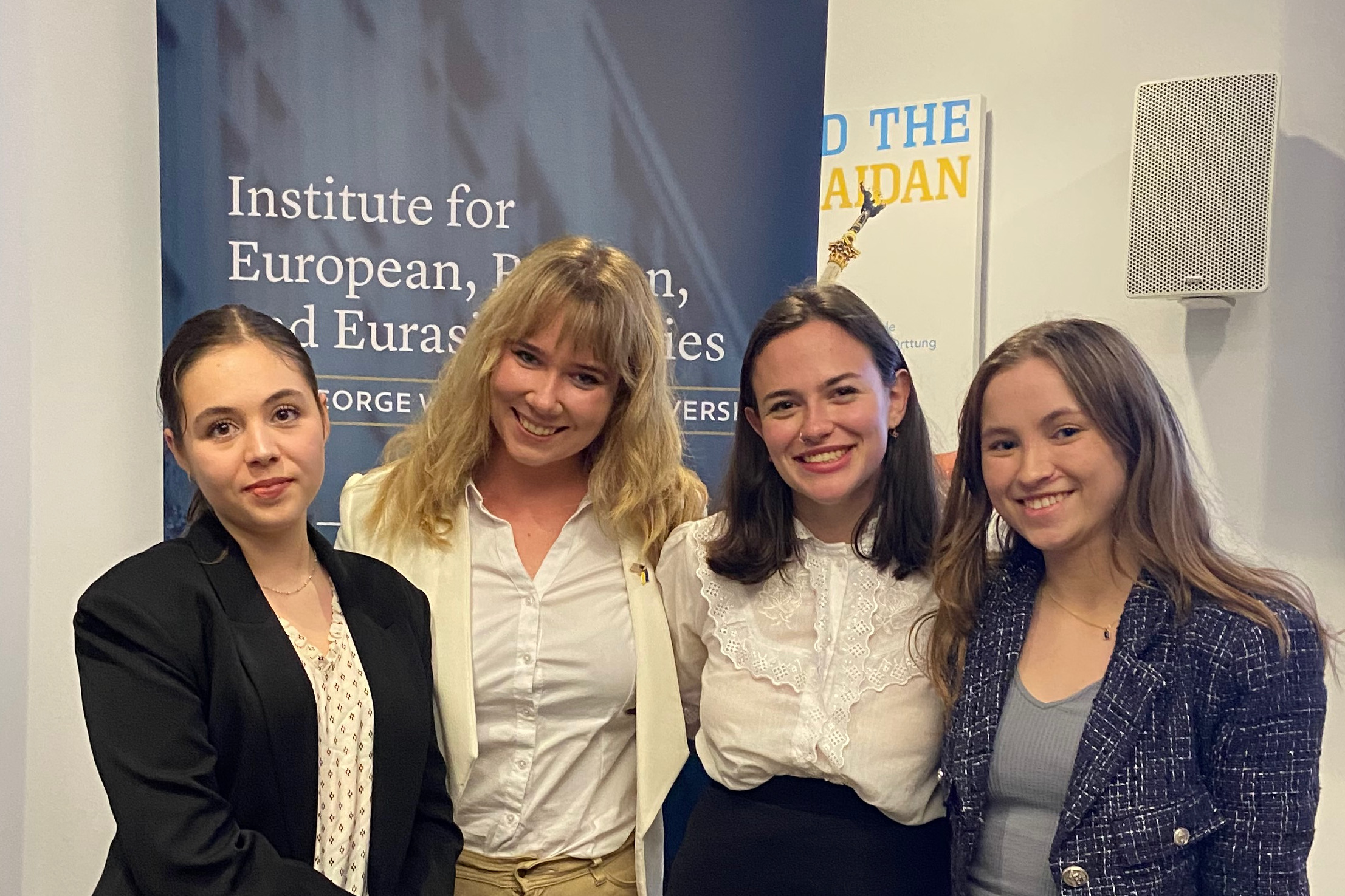 Four women in front of a sign