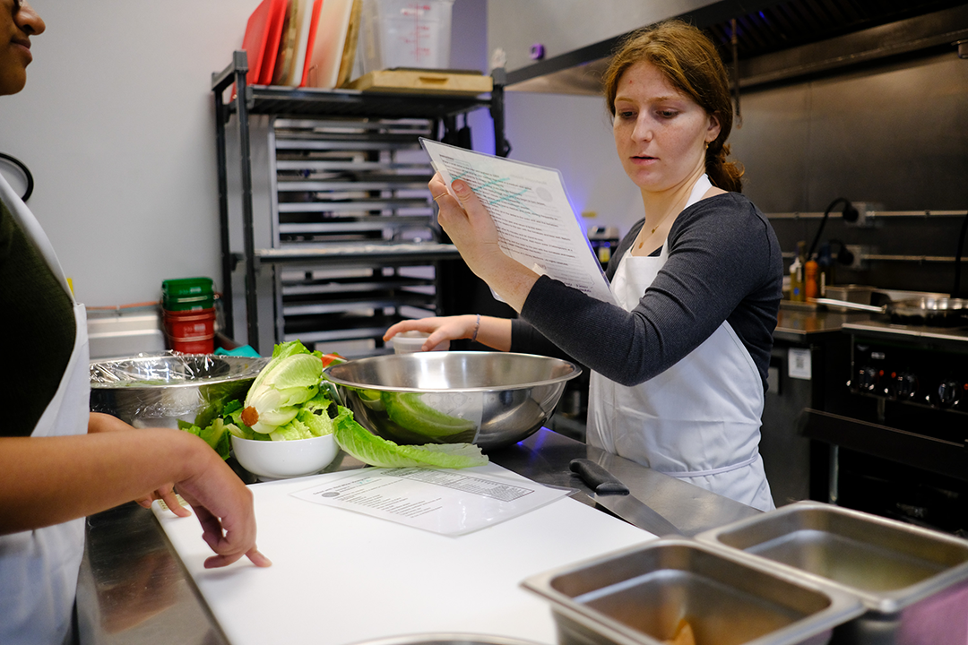 Sophomore Lexi Romanowsky in the kitchen looking at a menu to make a salad