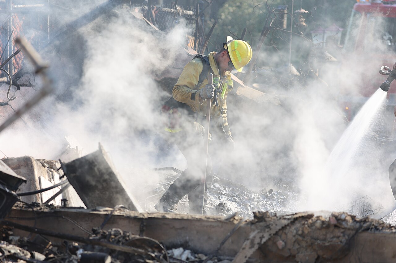 A firefighter moves through wreckage from the 2025 Eaton Fire. (Wikimedia Commons)