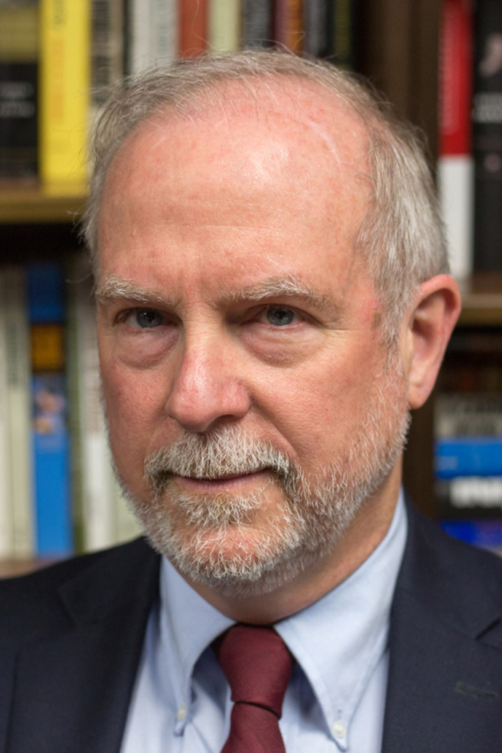 Eric Arnesen, the GW Teamsters Professor of History, in blue shirt & blazer, red tie, bookshelf behind him.