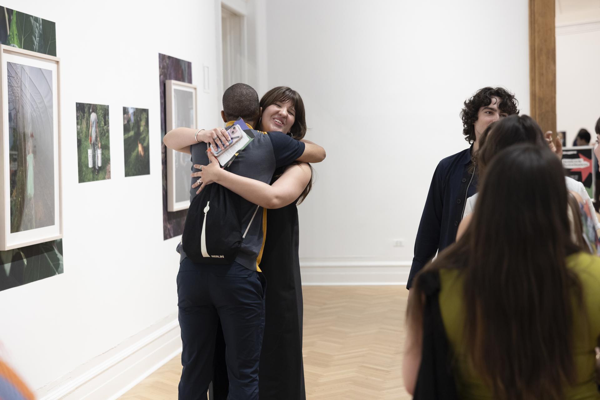 Photo: Cara Taylor Several guests cluster in a gallery; two of them share a hug