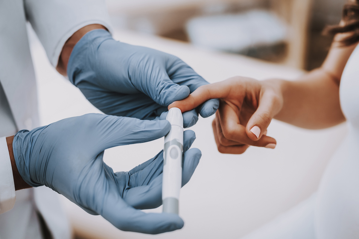 Doctor testing a person's blood glucose level
