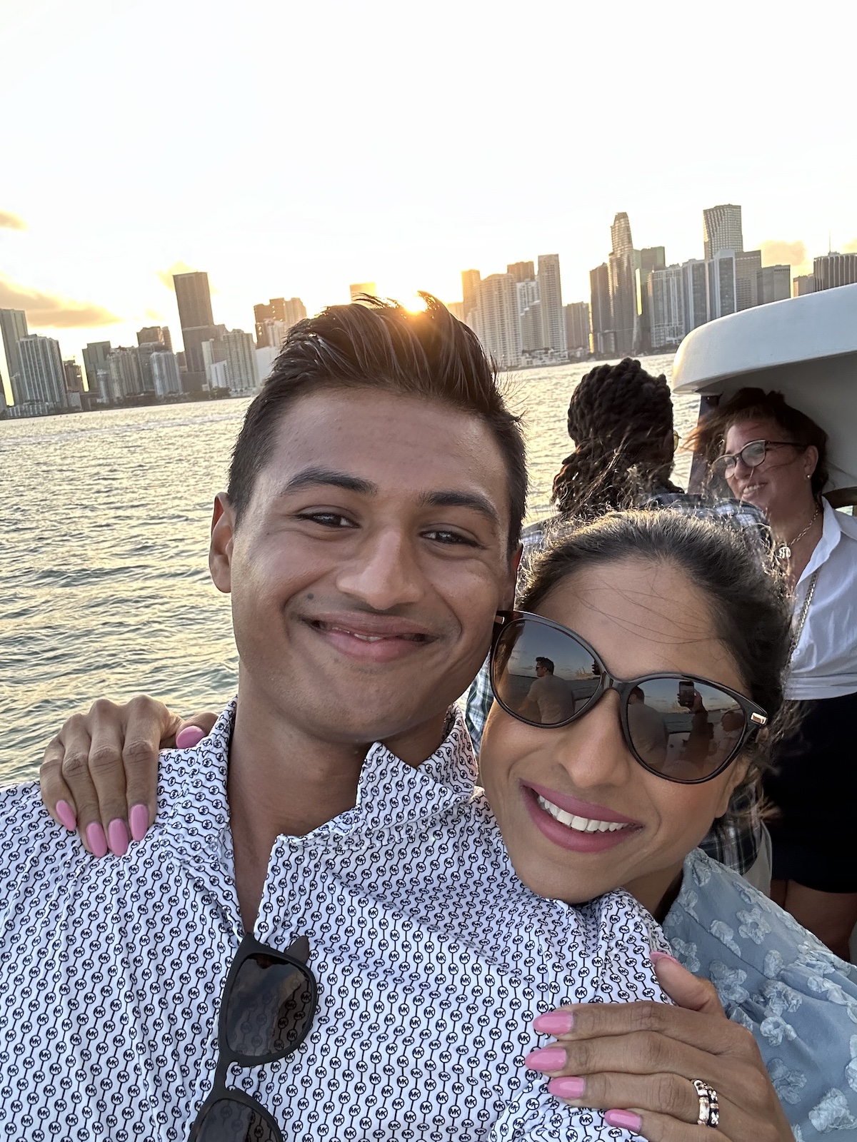 Arian Agadi and mother on a boat surrounded by water, with a city skyline
