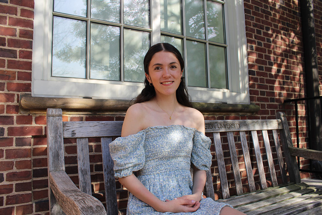 Junior political science and accounting major Emily-Anne Santiago  in a blue dress sitting on a bench