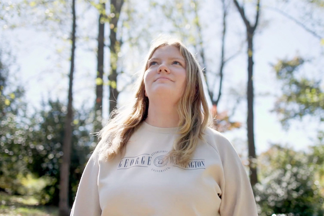 Riley standing outside in front of trees