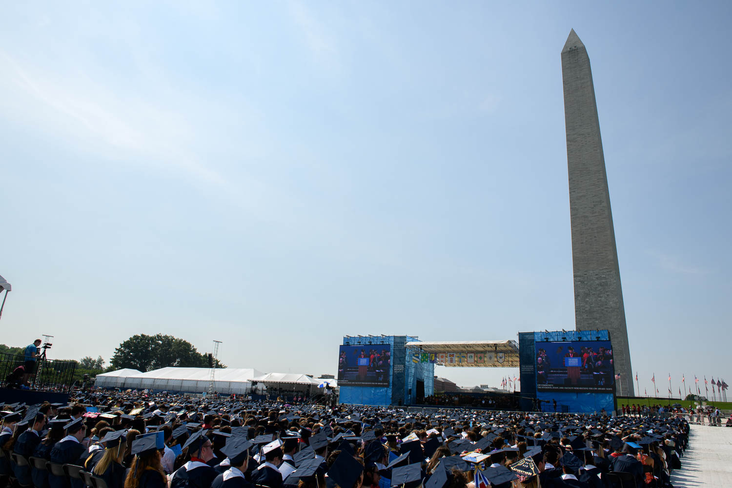 Washington Monument in background of Commencement stage with Guthrie speaking at podium