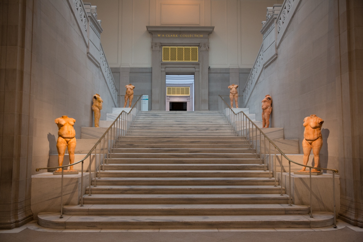 The stairs leading up to the Clark Collection gallery from the perspective of the foot of the stairs, which are flanked by statues.