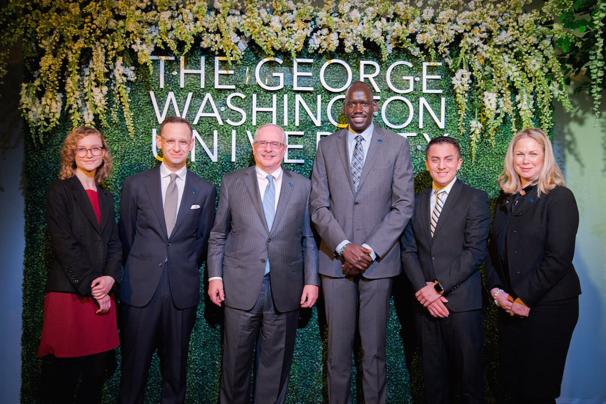 President LeBlanc stands with members of community in front of green wall, The George Washington University 