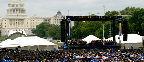 graduates on National Mall during commencement with Capitol as backdrop to university stage