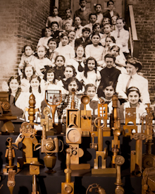 Installation, "Class Photo 2011," 30 1ft-tall bronze found object sculptures with Baltimore students from 1911 behind them