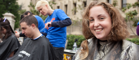 three students smile while getting haircuts at buzzing for change