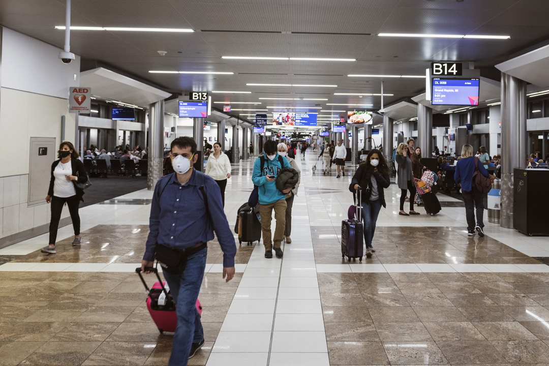 Passengers in an airport terminal traveling during COVID-19 pandemic.
