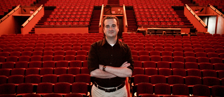 Carl Graci stands in front of empty seats in Lisner Auditorium audience