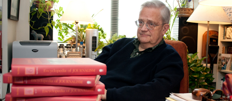 Chris Sterling sits at desk with a pile of his books in front of him