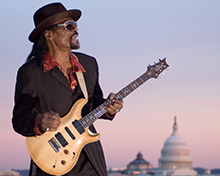 Chuck Brown plays guitar on rooftop with Capitol in background