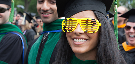 Class of 2012 graduate in regalia wears plastic sunglasses in shape of 2012