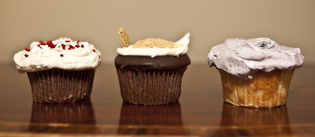 three chocolate cupcakes with vanilla icing lined up on wood table