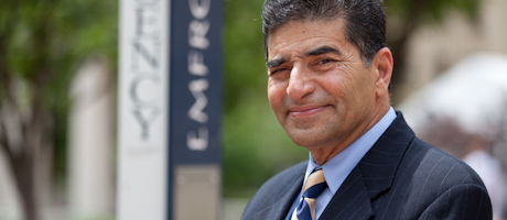 Elyas Malik smiles in front of campus blue light