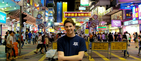 Ethan Elser smiling with arms crossed in Hong Kong street