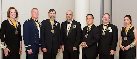 seven award winners in formal attire smile wearing awards 