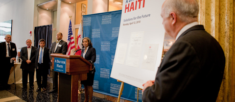 Steven Knapp viewing female speaker at podium at a Day for Haiti event