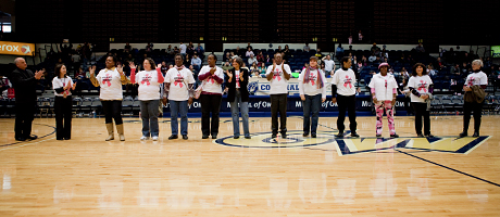 members of healing basketball stand on Smith Center court in t shirts with breast cancer ribbon