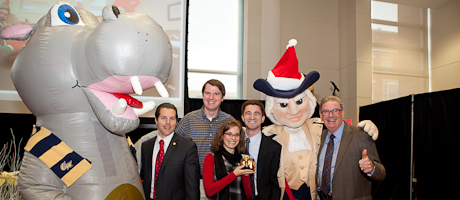 GW community celebrating at holiday party with hippo and George mascot