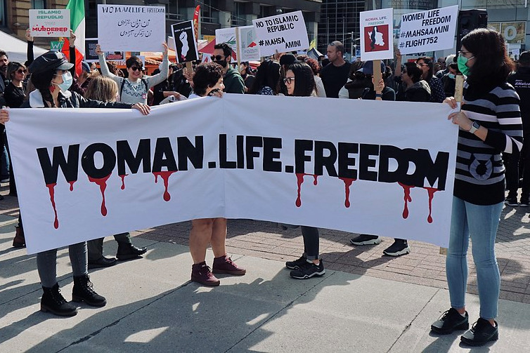 People holding a sign that reads Woman. Life. Freedom. 
