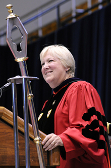 Jill Kasle holds university mace in regalia during commencement ceremony