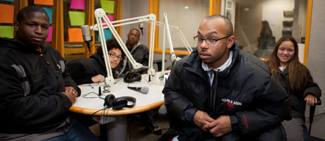students seated at table in WRGW studio surrounded by microphones