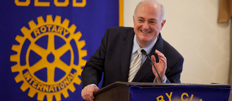 Steven Knapp speaks with Rotary flag behind him