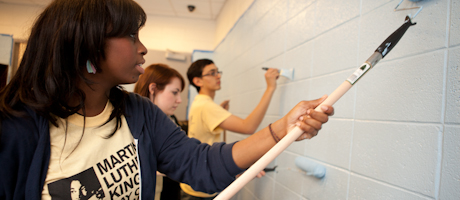 three students painting wall 