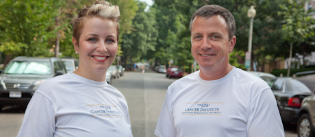 Julie Ost and Thom Kohout smile in GW Cancer Institute shirts 